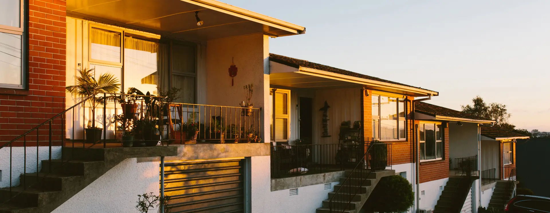 A row of connected townhouses lit by warm evening sunlight.