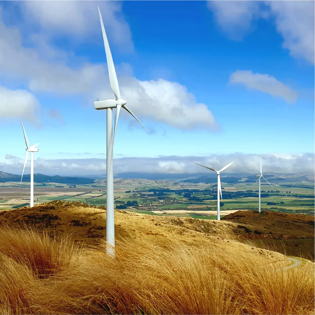 Wind turbines across rolling hills under a blue sky.