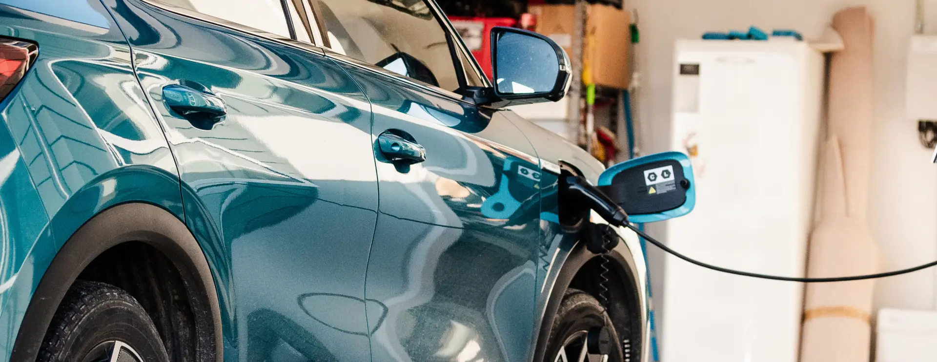 Close-up of an electric car plugged into a home charging unit in a garage.