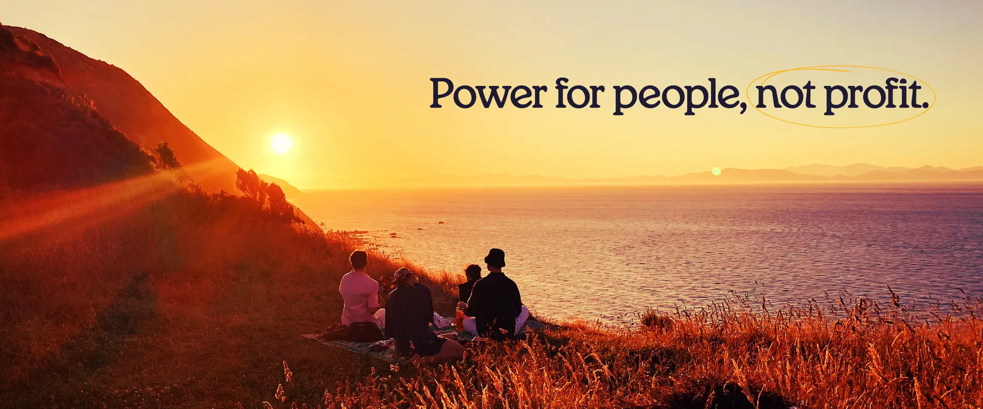 Four people sitting on a hillside at sunset, looking out over the ocean, with the text ‘Power for people, not profit.'