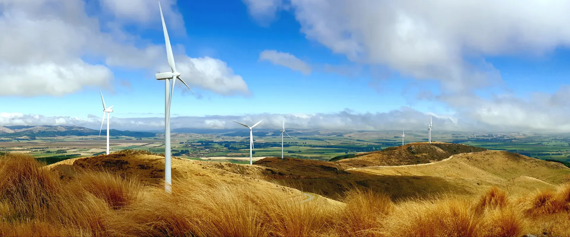 Wind turbines across rolling hills under a blue sky.
